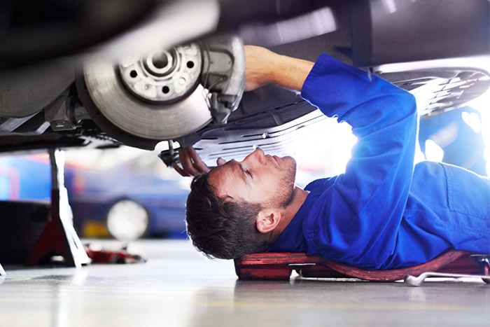mechanic underneath car checking out parts