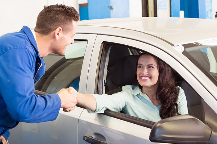 mechanic shaking hands with customer in fixed car