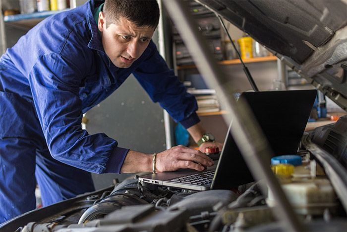 man checking engine with computer system